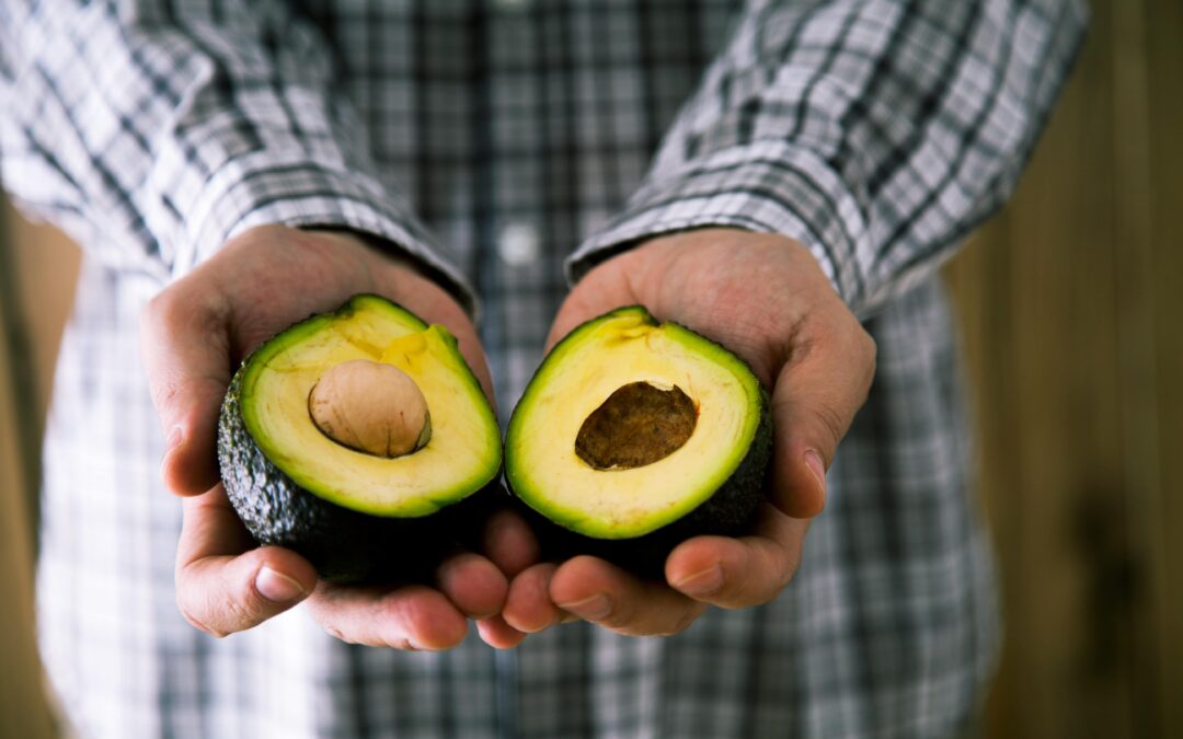 man holding cut open avocado