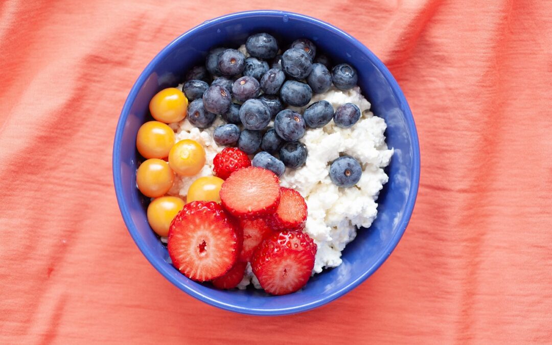 cottage_cheese_with_strawberries_blueberries_in_blue_bowl_on_pink_background