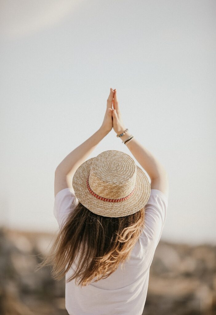 a_woman_wearing_a_hat_and_holding_her_hands_together