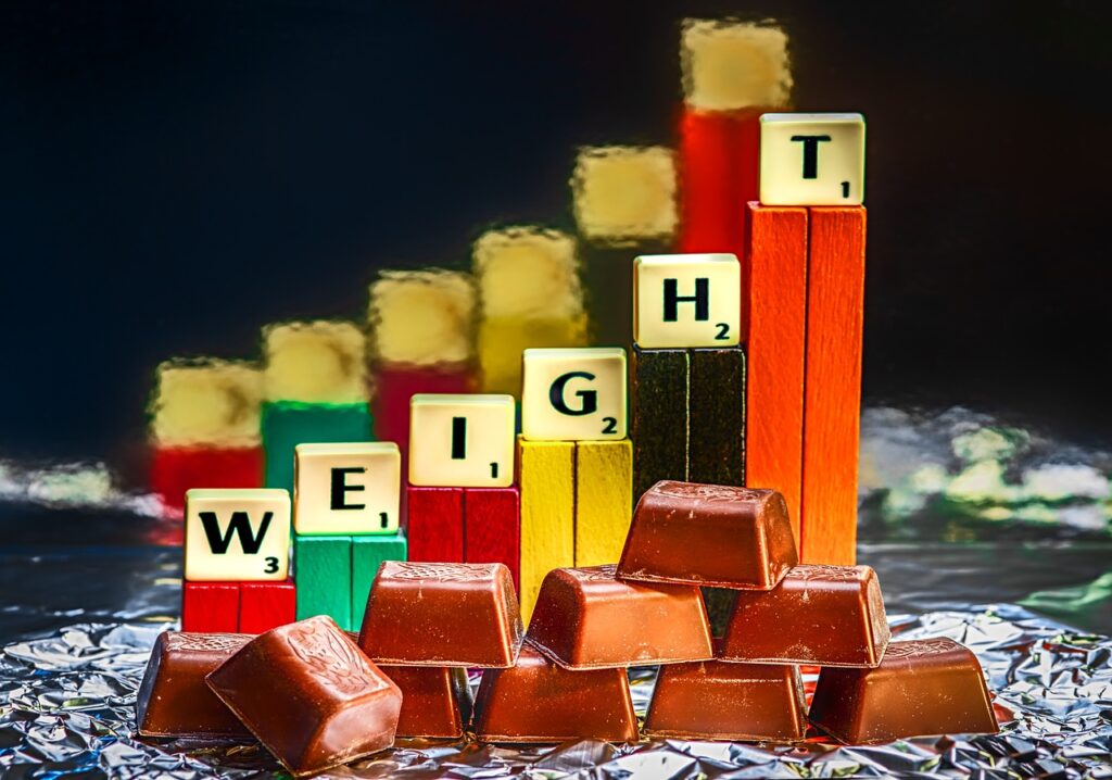 a group of chocolate bars and scrabble letter squares spelling out the word weight