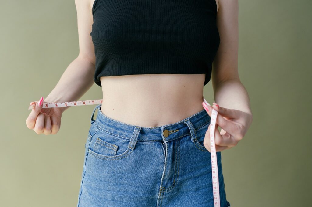 woman measuring her waist with tape measure