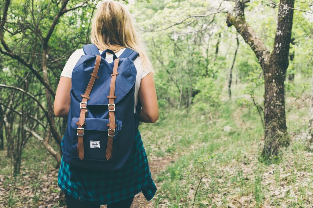 blonde woman with backpack hiking in the woods