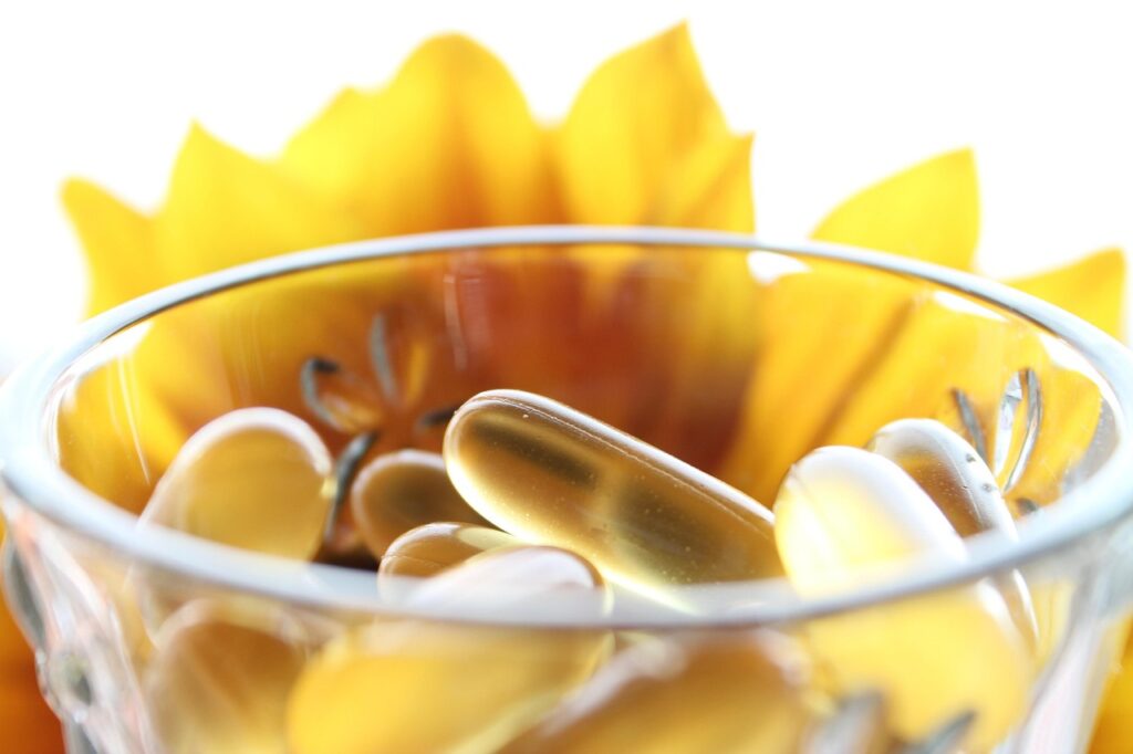 gel capsule supplements in glass in front of a yellow flower