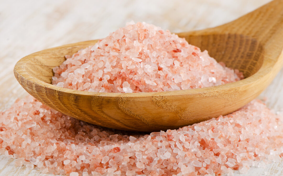 wooden spoon filled with pink sea salt crystals